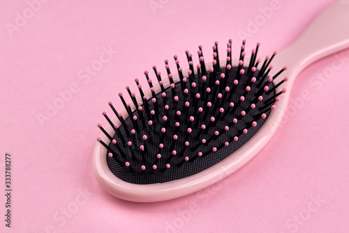 pink hairbrush isolated on a pink coral background with space. beauty hair accessory for hairstyle.