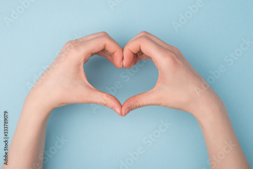 Top pov above overhead close up view photo of hands making shape of heart isolated over blue pastel color background