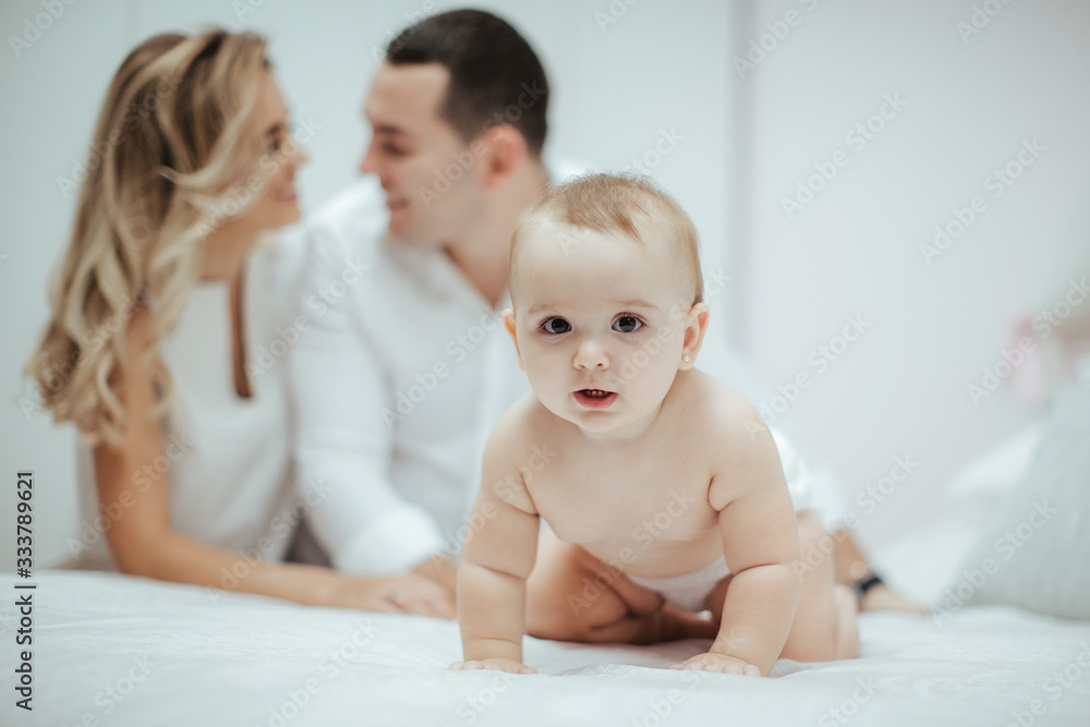Smiling young couple playing with their beloved newborn baby girl on the bed Smiling young couple playing with their beloved newborn baby girl on the bed