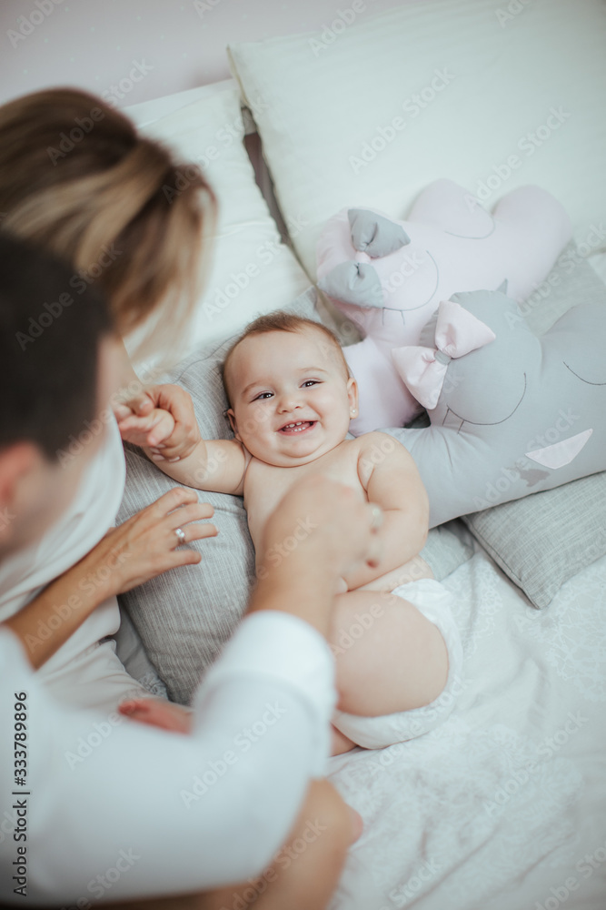 Smiling young couple playing with their beloved newborn baby girl on the bed Smiling young couple playing with their beloved newborn baby girl on the bed