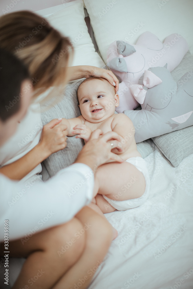 Smiling young couple playing with their beloved newborn baby girl on the bed Smiling young couple playing with their beloved newborn baby girl on the bed