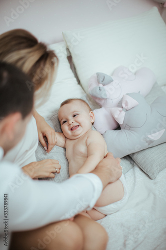 Smiling young couple playing with their beloved newborn baby girl on the bed © sergiubirca