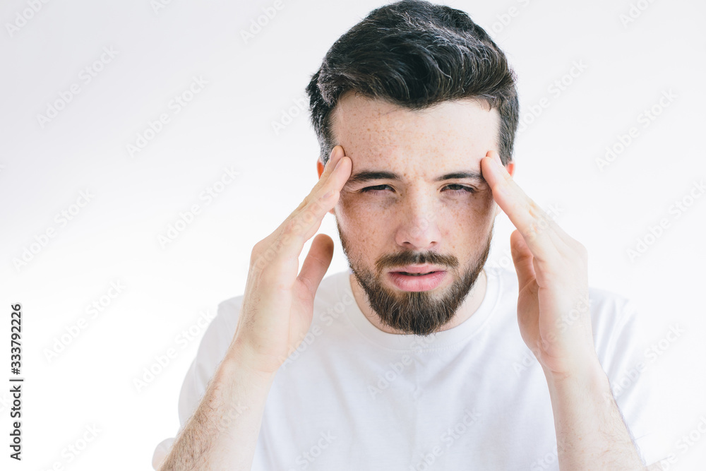 Young bearded man suffer from headache, Hold fingers on head and look on camera. Need pain relief or pill from ache. Stand alone isolated over background. Young bearded man suffer from headache, Hold fingers on head and look on camera. Need pain relief or pill from ache. Stand alone isolated over background.