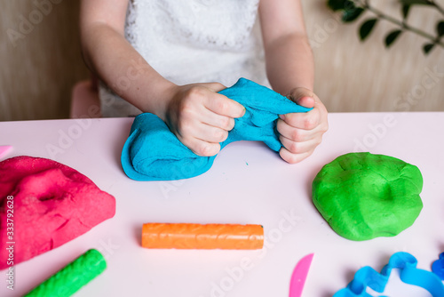 Child hands playing with colorful clay. Homemade plastiline. Plasticine. play dough. Girl molding modeling clay. Homemade clay.