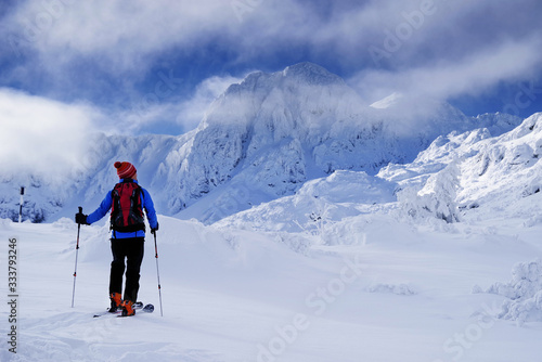 Ski touring in harsh winter conditions. Ski tourer sporting in in the mountains. Winter alpine landscape