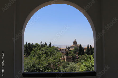 A view of Alhambra palace and fortress complex through a window at Generalife gardens in Granada, Andalusia, Spain.