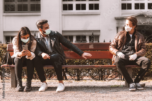 corona - covid-19 social distancing concept picture with three people wearing face masks - stay away
