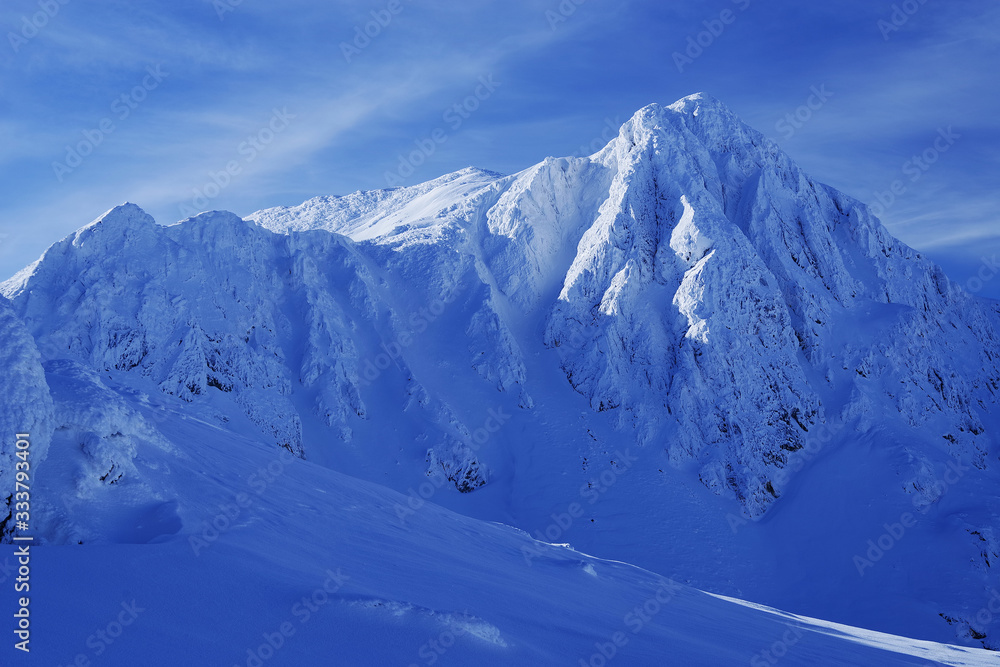 Bucura II Peak, 2372m. Winter alpine landscape in National Park Retezat, Carpathians, Romania, Europe. Snow covered moutains scenery