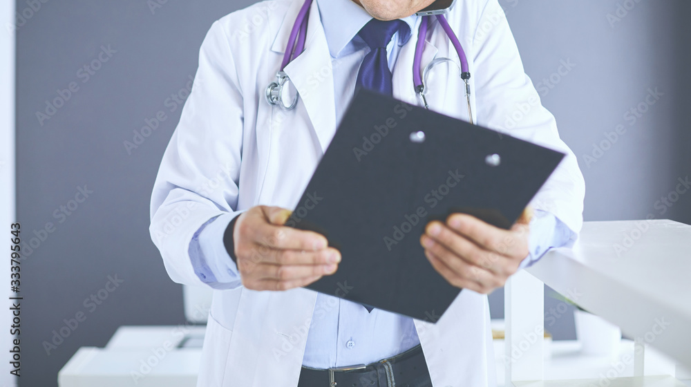 Male doctor writes notes on the clipboard in the hospital Male doctor writes notes on the clipboard in the hospital
