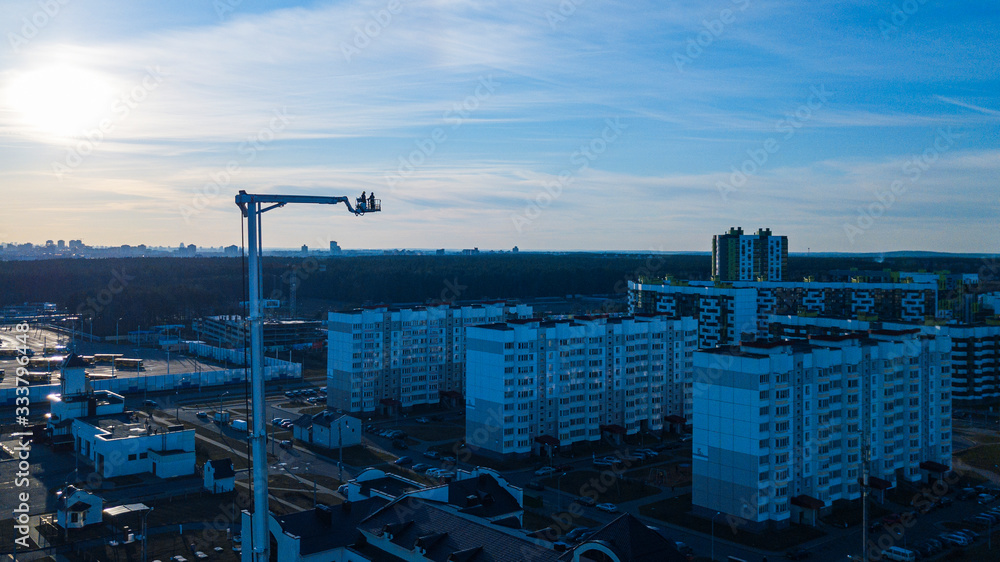 Fototapeta premium Fire department truck ladder extended on classic blue sky and panoramic view of city background. Aerial view.