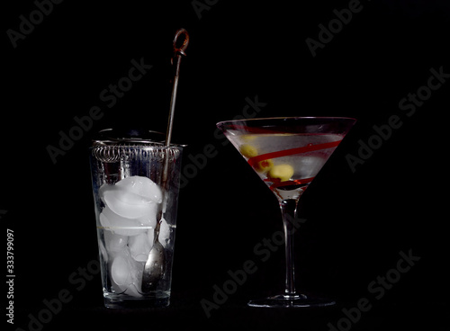 Martini on a Black Background, Stirred, Not Shaken, with Three Olives, and the Mixing Glass, Spoon, Strainer, and Ice