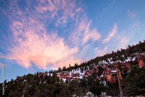 Bright pink clouds at sunset over orange sandstone cliffs in Utah Desert.