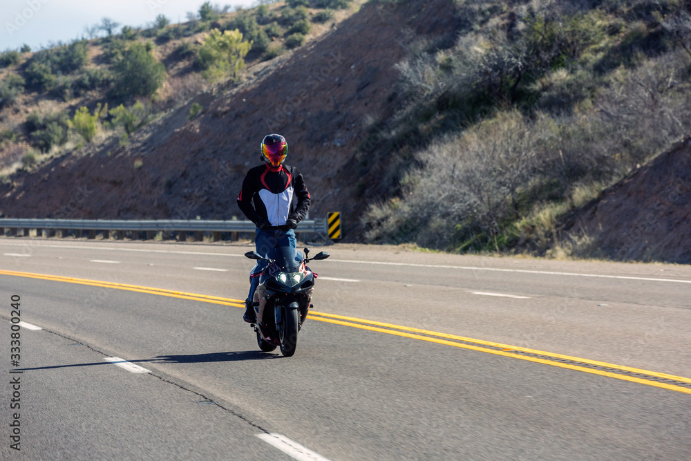 Motorcycle rider on a mountain road standing up on his bike