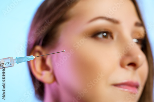 Syringe for beauty injection on the background of the face of a girl closeup. Beautiful female model with healthy skin 
