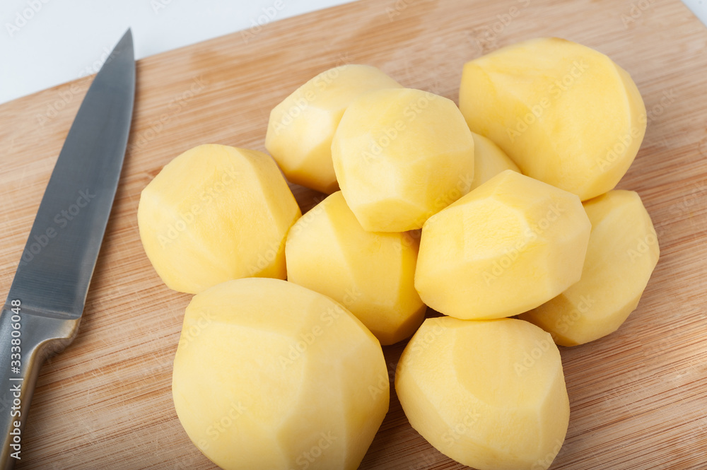 peeled potatoes lies on a kitchen wooden cutting board. isolate on white background peeled potatoes lies on a kitchen wooden cutting board. isolate on white background