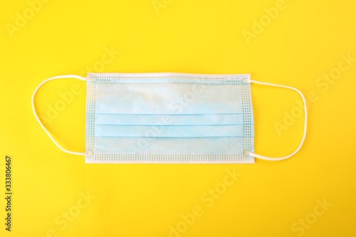 A one-use surgical mask isolated on yellow background