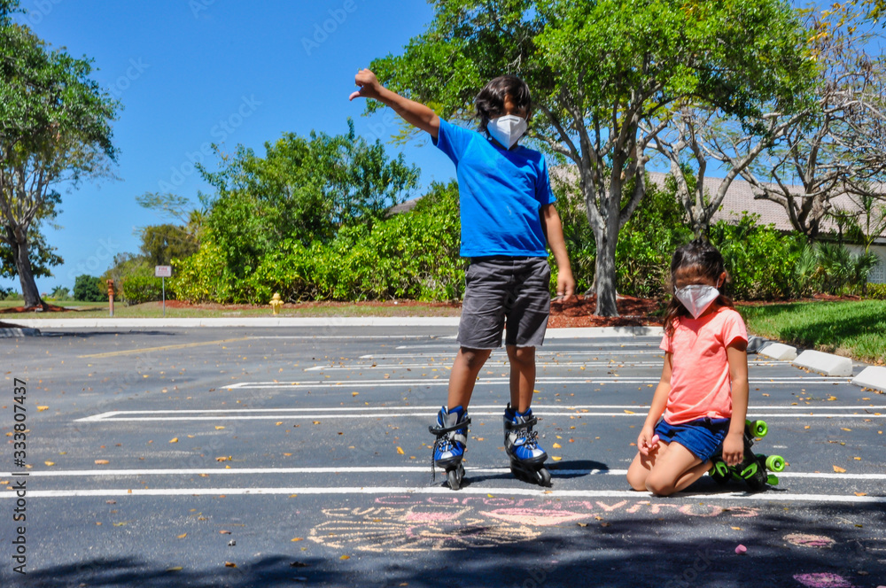 Obraz premium coronavirus kids mask boy thumbs down girl stare heads up side to side stare rollerblades pointing drawing chalk outside arts roller skates covid19