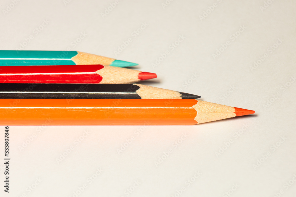 Orange, black, red, blue pencils bright pencils on a on light paper Orange, black, red, blue pencils bright pencils on a on light paper