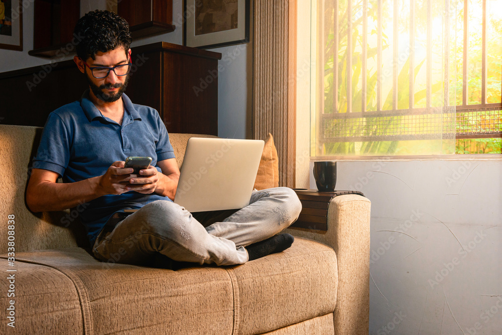 Hispanic sending message via cell phone while working at his home. Hispanic sending message via cell phone while working at his home.