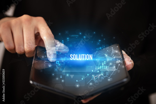 Businessman holding a foldable smartphone with SOLUTION inscription, business concept