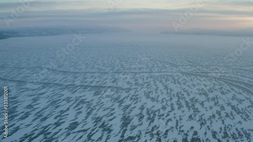 Aerial drone shot of a frozen lake, blocks of ice, frozen trees, reflections, typical house during the winter of polar Lapland.