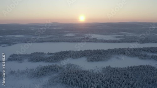 Aerial drone shot of a frozen lake, blocks of ice, frozen trees, reflections, typical house during the winter of polar Lapland.
