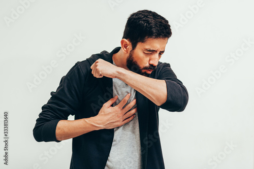 Sick man coughing in his arm joint to avoid spreading coronavirus. Covid-19. photo