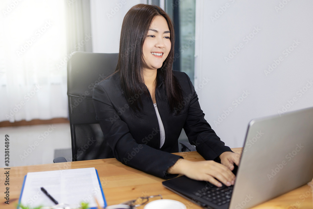 Happy asian woman Smiling and working her laptop on desk. Business woman concept in modern office. Happy asian woman Smiling and working her laptop on desk. Business woman concept in modern office.