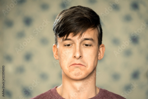 Portrait of a young man with dark hair with a sad face. Horizontal frame