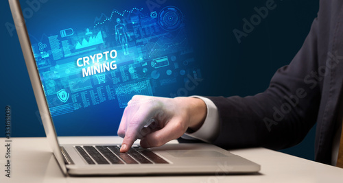 Businessman working on laptop with CRYPTO MINING inscription, cyber technology concept