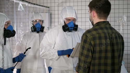 Team in protective suits temperature measuring of a civil man in a hospital. Coronavirus, COVID-19 photo