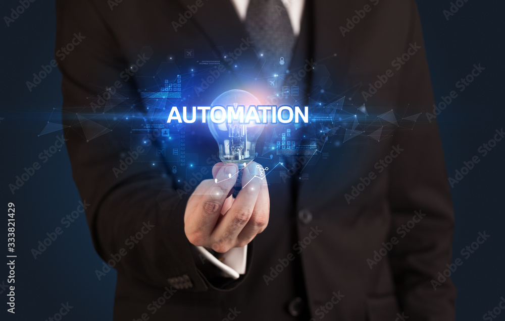 Businessman holding light bulb with AUTOMATION inscription, innovative technology concept Businessman holding light bulb with AUTOMATION inscription, innovative technology concept