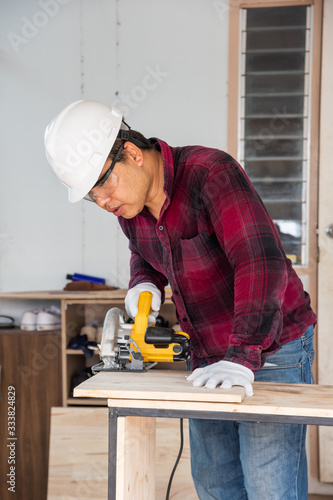 Worker cutting wood with power saw