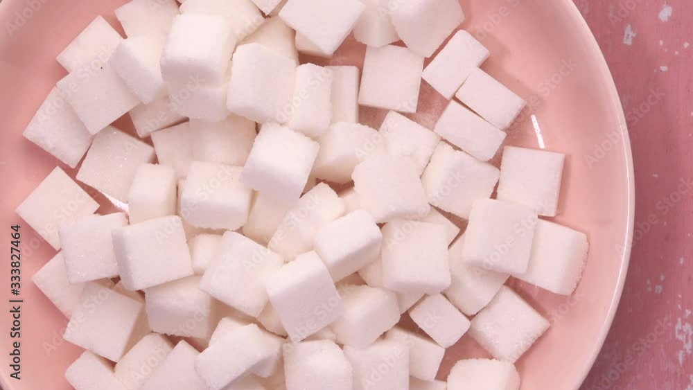 top view of sugar cube in a bowl on pink background. top view of sugar cube in a bowl on pink background.