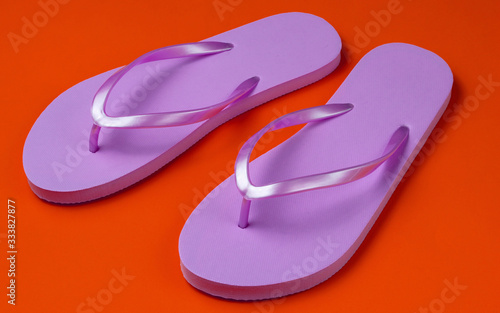 Trendy beach pink flip flops on orange background.