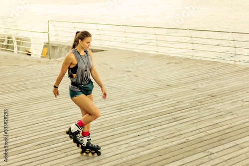 Obraz na plátně Young attractive sport woman roller skating on the beach