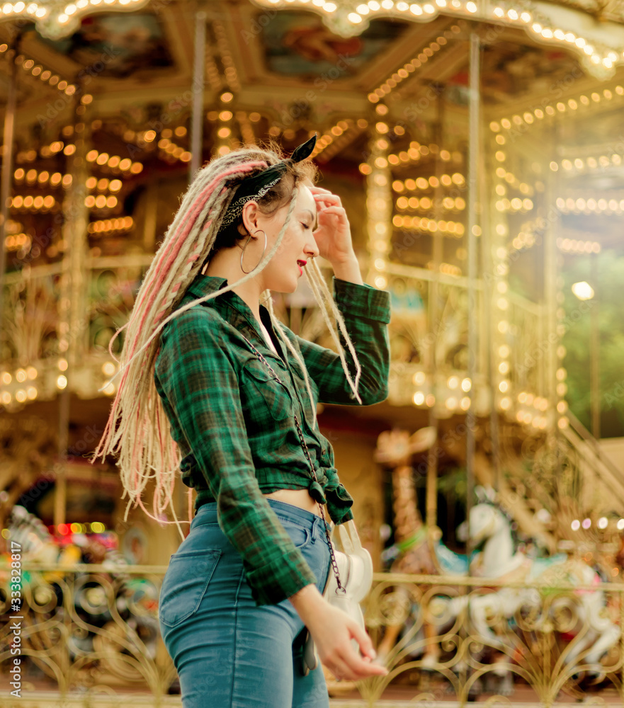 Obraz premium Cheerful emotional woman with dreadlocks hairstyle in an amusement park. Lifestyle Concept