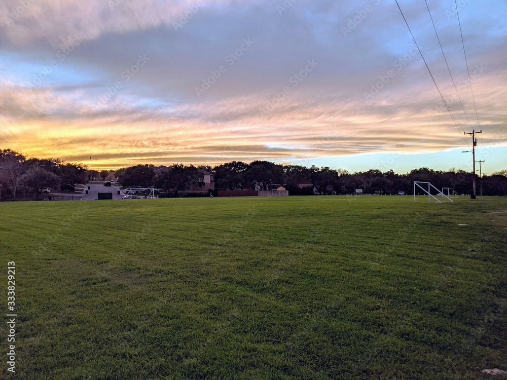 A suburban park with soccer fields at sunset