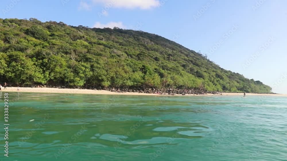 A Small Boat Motoring Slowly Through Turquoise Water By A White Sand Beach And Lush Green Forest Headland On A Hot Sunny Day A Small Boat Motoring Slowly Through Turquoise Water By A White Sand Beach And Lush Green Forest Headland On A Hot Sunny Day