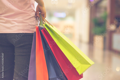 Close up photo of woman hand holding colorful shopping bags