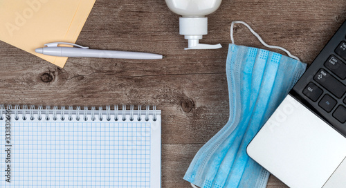 hygiene in the office. remote work kit on wooden desk. sanitizer gel and face mask photo