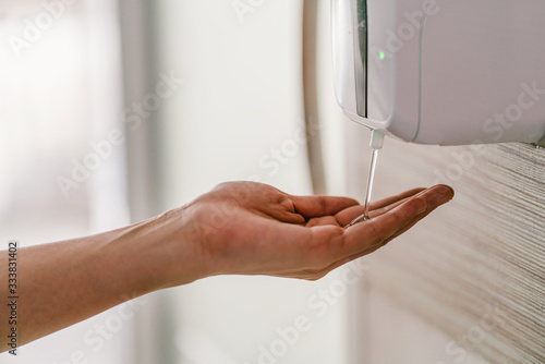 Closeup Asian woman hand using wash hand sanitizer gel dispenser automatic machine before work while Coronavirus Network Outbreak, health care and cleaning for prevent covid19 concept photo
