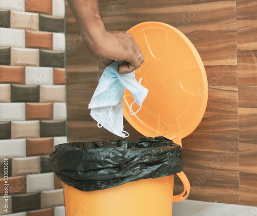 Φωτογραφία Hands throwing medical mask into closed bin - Covid-19, Coronavirus advice to discard or dispose medical mask to closed trash can after usage - concept showing to do hygiene practice