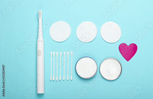 Flat lay composition of hygiene products. Toothbrush  cotton pads  ear sticks  cream on a blue background. Top view