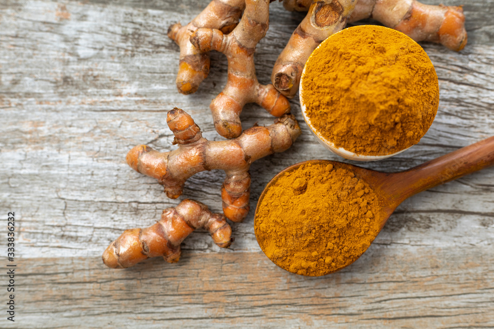 Turmeric (curcumin) powder and fresh rhizome on a wooden background. Turmeric (curcumin) powder and fresh rhizome on a wooden background.