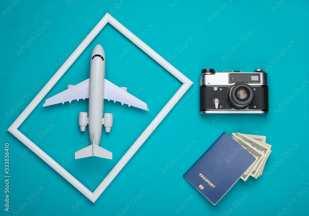 Flat lay travel composition. Retro camera, passport and airplane in a white frame on blue background. Top view Flat lay travel composition. Retro camera, passport and airplane in a white frame on blue background. Top view