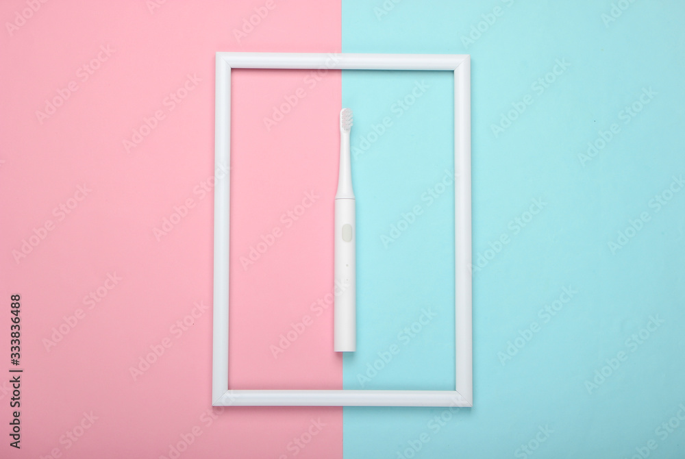 Electric toothbrush on pink blue pastel background with white frame. Studio shot. Creative flat lay. Top view. Minimalism