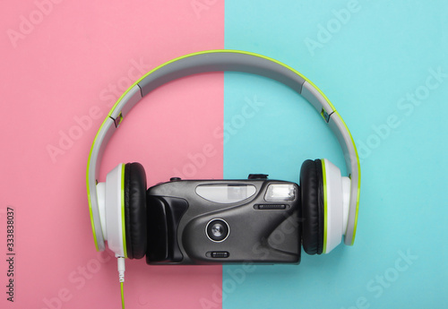 Stereo headphones with a retro film camera on yellow background. Top view