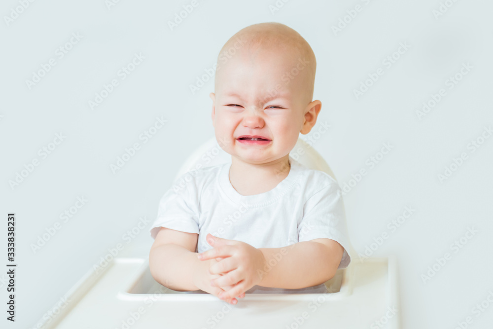 Upset baby boy sitting on white background Upset baby boy sitting on white background