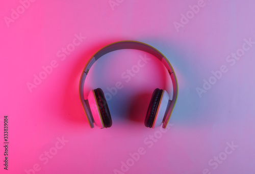 Modern stereo wireless headphones with neon pink blue light. Gradient glow. Top view